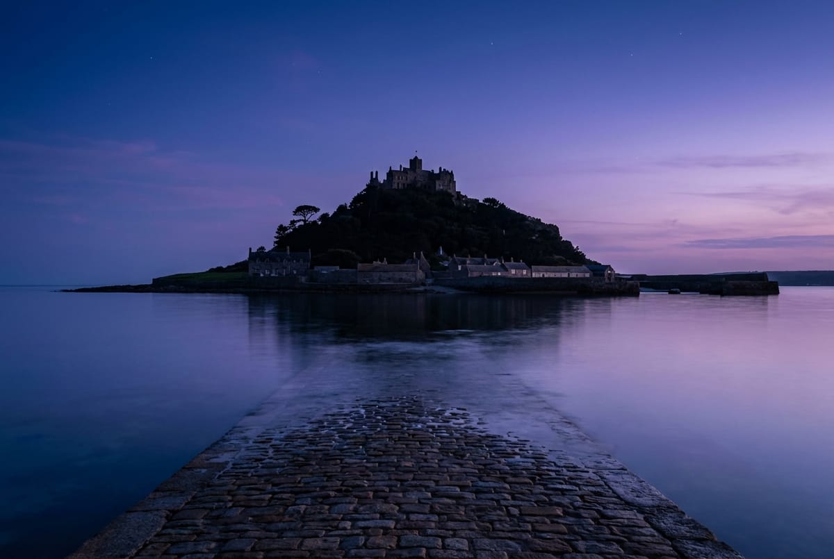 St Michael's Mount at dusk, rising from calm waters with a pastel sky