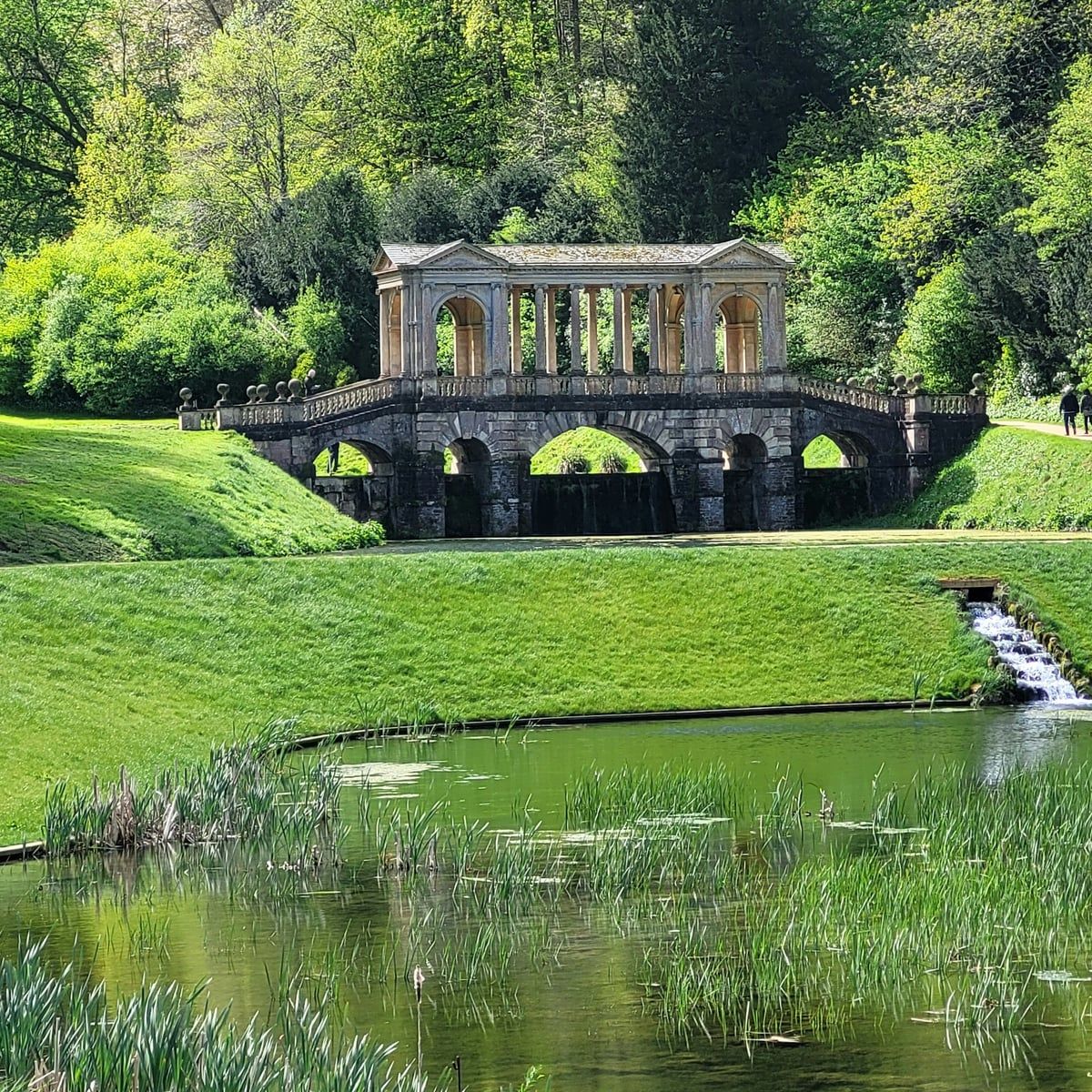 The Palladian bridge at Prior Park above Bath, reflected in the lake beneath wooded slopes
