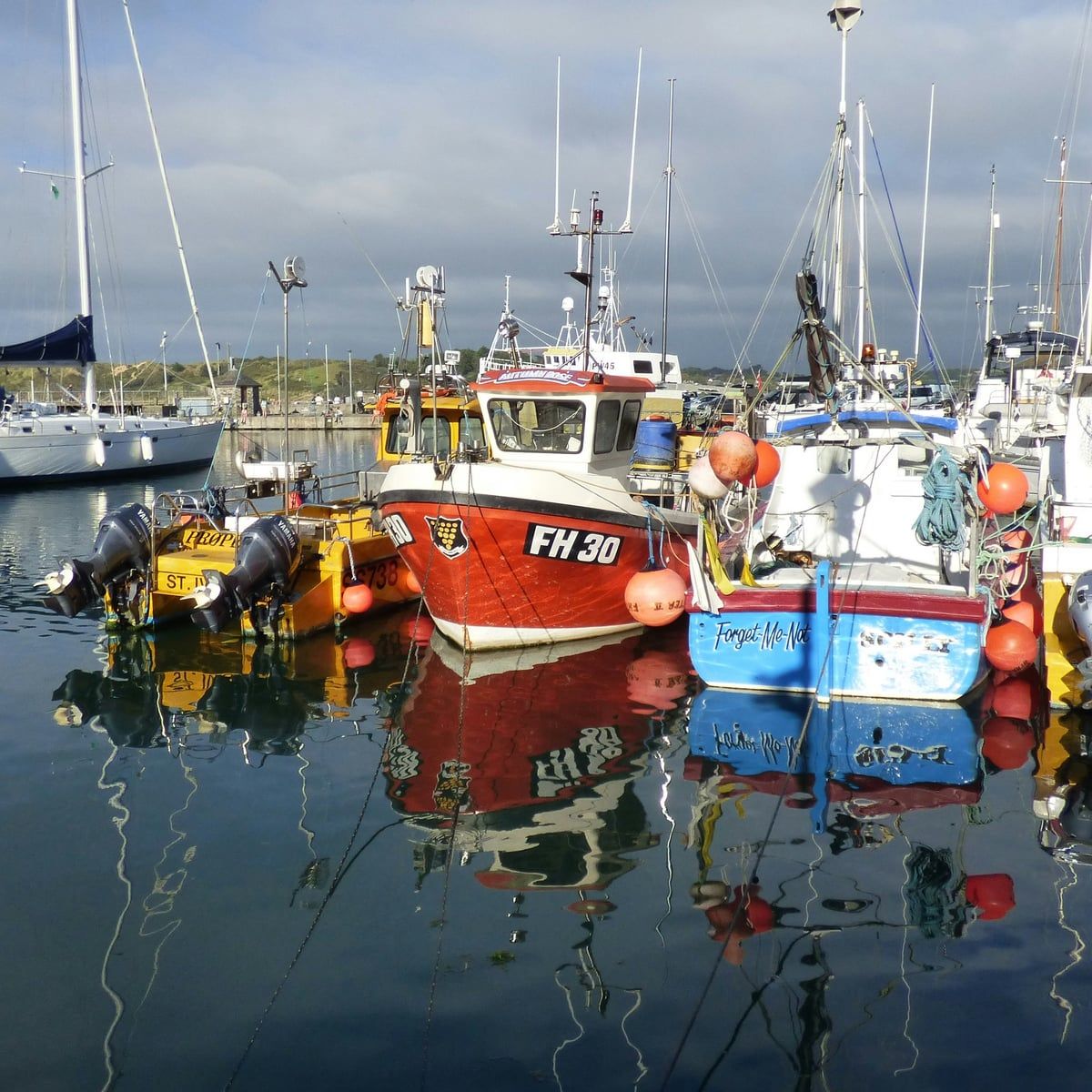 Fishing boats moored in Padstow harbour, reflected in still water