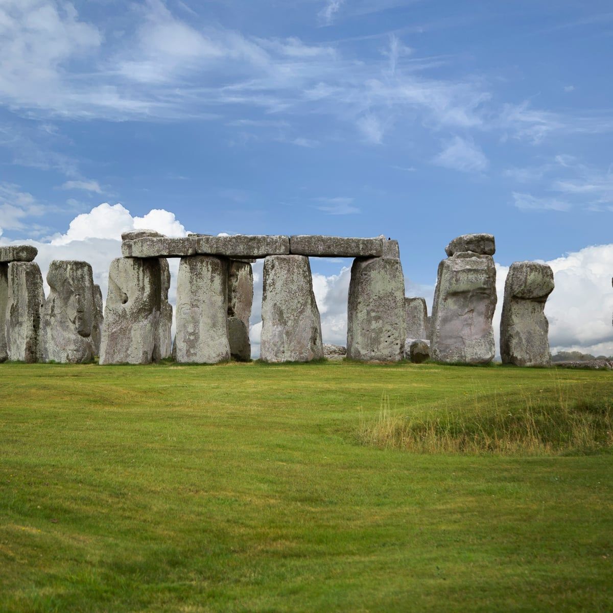 The standing stones of Stonehenge on open grassland under a blue sky