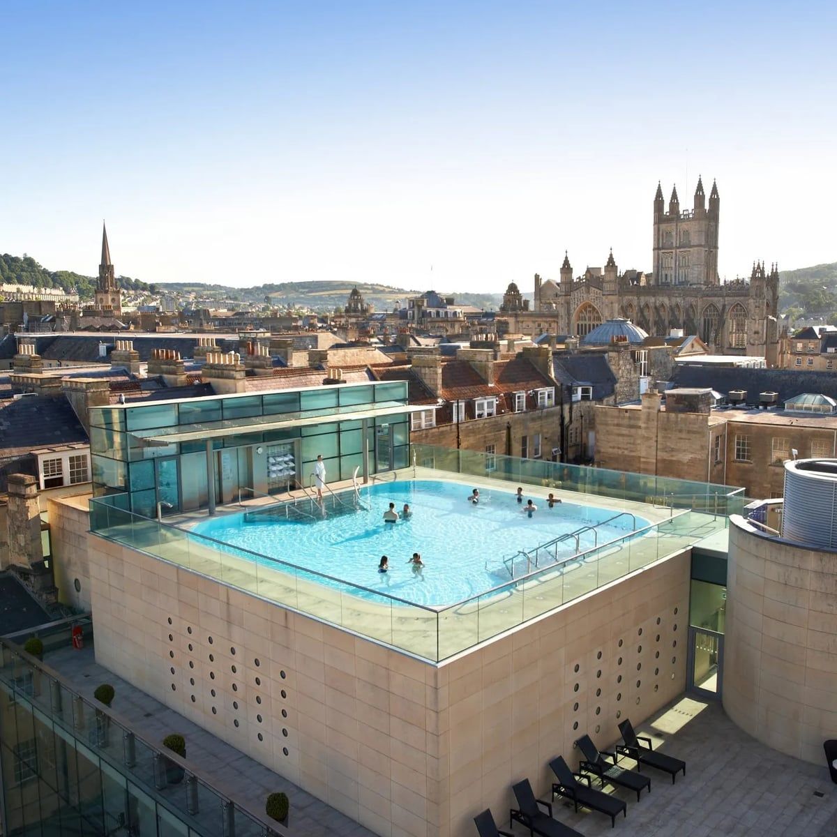 Bathers in the rooftop pool at Thermae Bath Spa, the Abbey tower on the skyline behind