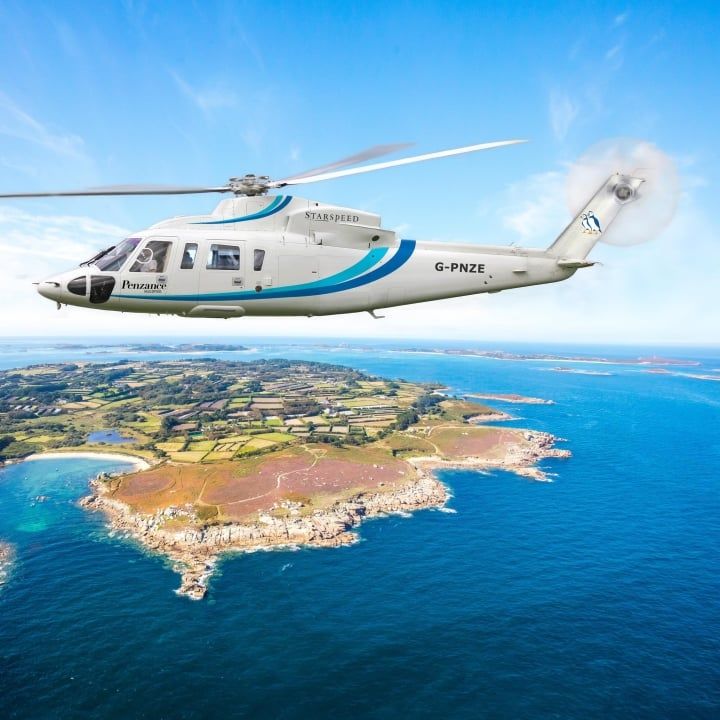 A helicopter in flight over the Isles of Scilly, the islands and bays in bright sunshine below