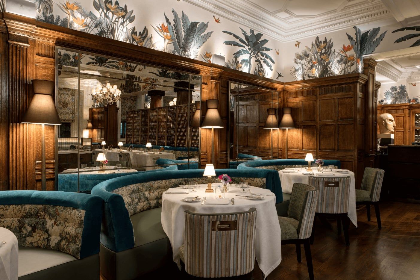 The wood-panelled dining room at Brown's Hotel, teal banquettes and white tablecloths beneath a painted botanical frieze