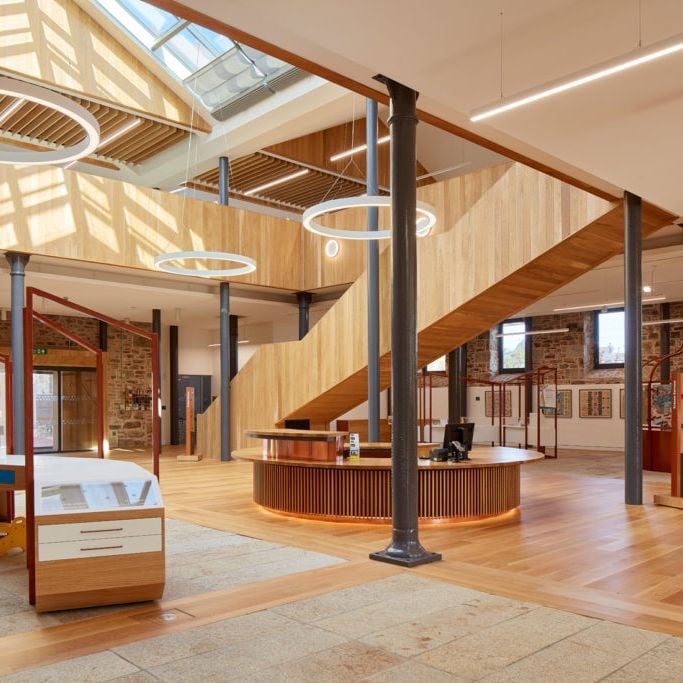 The timber-lined hall at Kresen Kernow, with a sweeping oak staircase and exhibition cases beneath skylights