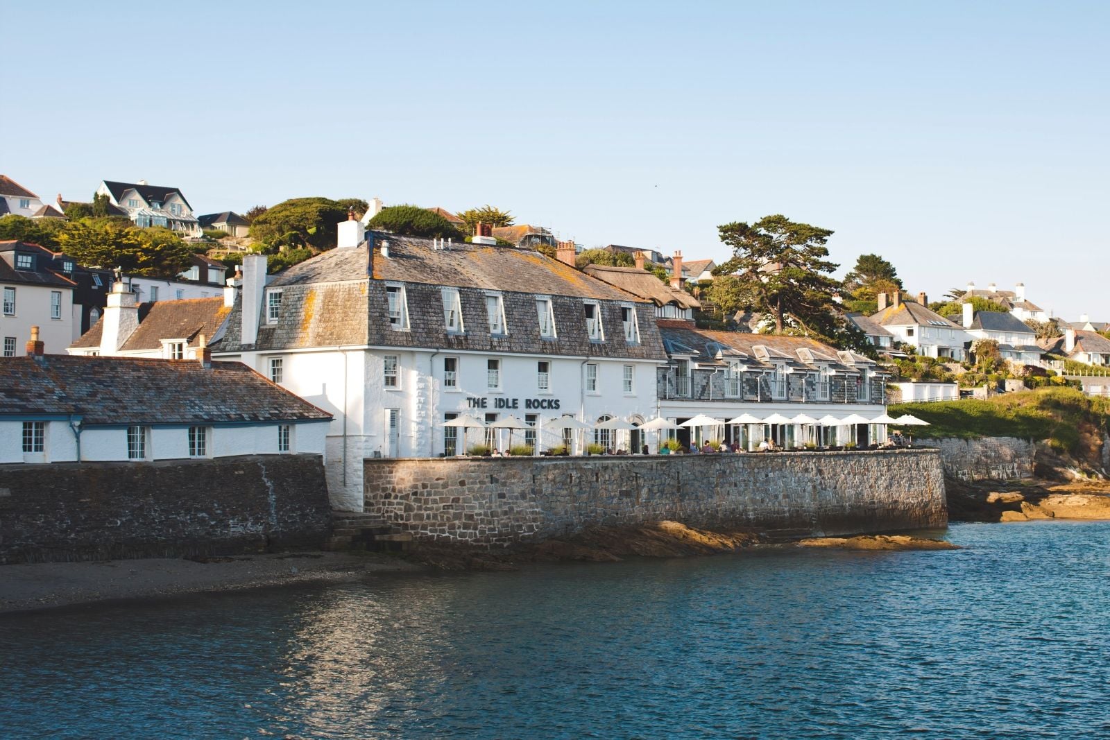 The Idle Rocks, a white slate-roofed hotel on the harbour wall at St Mawes, parasols set out along its terrace