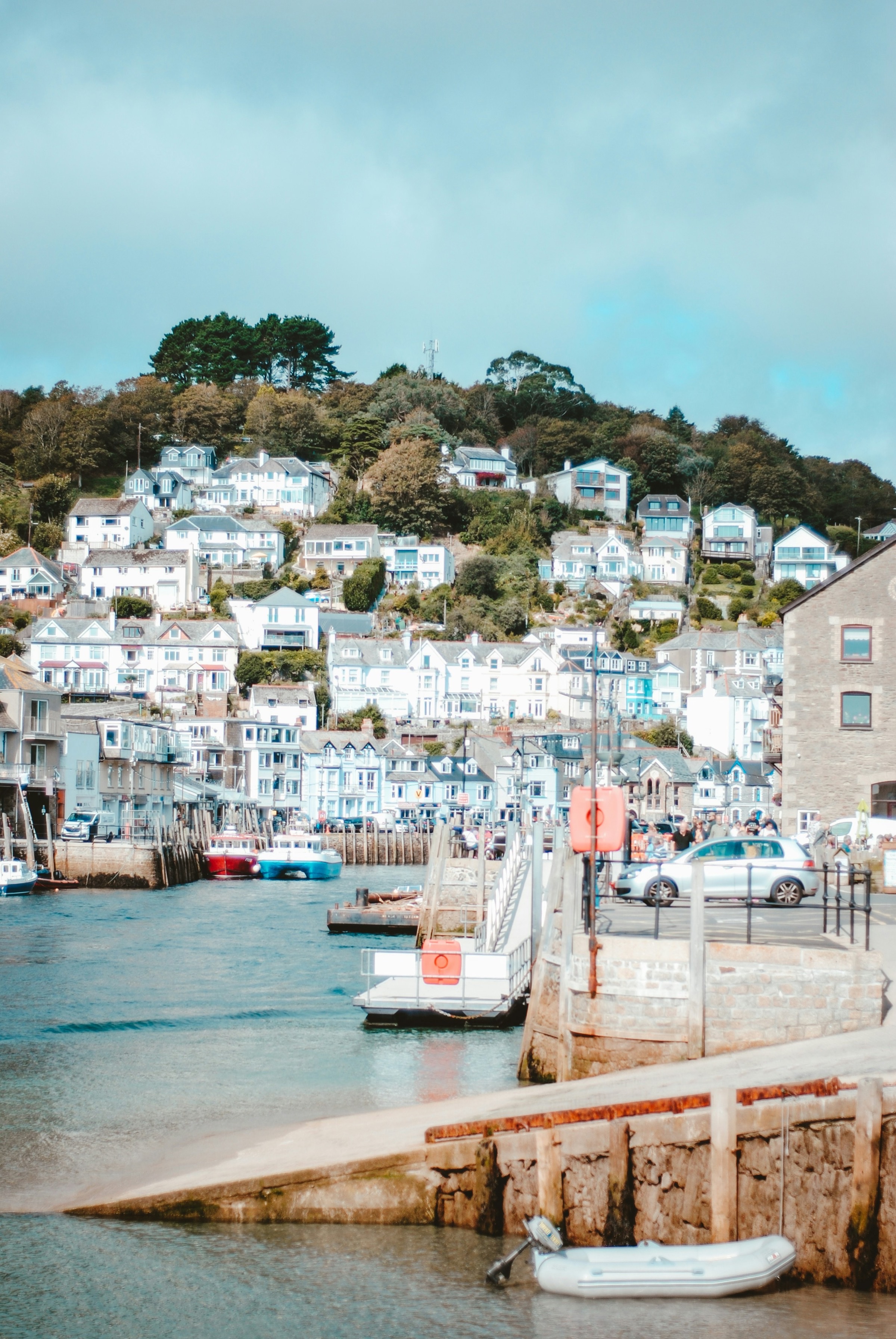 A hillside of pastel-painted houses above a harbour of small moored boats